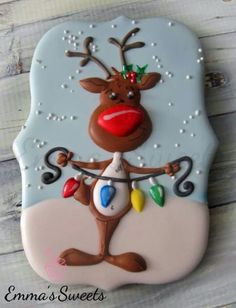 a decorated cookie with a reindeer holding a christmas ornament on it's face