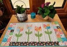 a quilted table runner with flowers and potted plants