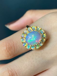 RING DETAILS: ✪Design: Gold ring ✪Gemstone: Opal ✪Gemstone shape: Cabochon oval ✪Gemstone size: Center stone: 12x10mm Oval, side stones: 3mm round ✪Setting type: Cluster ✪Metal type: 14k solid yellow gold (also available in white and rose gold, please select at checkout) ✪Total ring weight: 7 grams ✪Metal finish: Smooth shiny Choose your ring size from drop down menu and if you need any other preferred ring size please contact us. QUALITY OF MATERIALS: Metal: Most of our jewelry at JewelryMansio Fine Jewelry Multi-stone Round Cut Opal Ring, Fine Jewelry Opal Ring With Multi-stone Round Cut, 14k Gold Multi-stone Opal Ring, Yellow Gold Cluster Rings With Multi-stone, 14k Gold Opal Ring With Multi-stone Round Cut, Cluster Multi-stone Opal Ring For Anniversary, Opal Multi-stone Round Cut Rings, Yellow Gold Cluster Jewelry With Halo Setting, 14k Gold Cluster Ring With Accent Stones