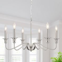 a chandelier with six lights hanging from it's center in a dining room