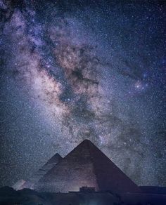 the great pyramids are lit up at night with stars in the sky above them