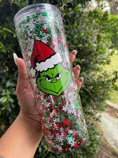 the grin face on this tumbler is covered in glitter and has a santa hat