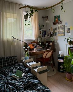 a bedroom with a bed, desk and plants on the window sill in it