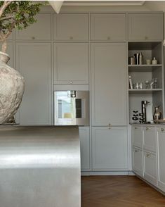 a large vase sitting on top of a metal counter in a kitchen next to cabinets