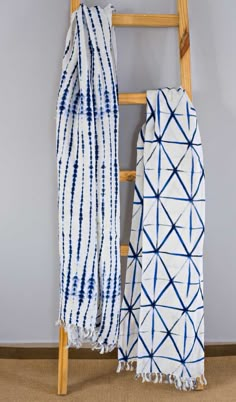 two blue and white scarves hanging on a ladder