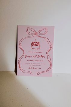 a pink wedding card with a cake on it and a bow at the top is shown