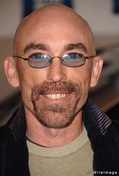 a bald man with glasses and a brown shirt