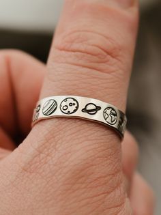 "Copy and paste into your browser, get 15% off ➔ https://bit.ly/VD15OFF For the space lovers in your life, this ring features celestial hands with the sun and the moon, centered by planets from the solar system. DETAILS: -Each ring is hand stamped -Ring is Sterling Silver, Fine Silver, or Gold Filled -6mm in thickness You will receive one hand-stamped ring filled with a black enamel finish. **Every item is handmade, this means that each will be unique and may not look EXACTLY like the picture, b Black Silver Ring, Cool Assessories, Minimalist Moon Phase Midi Rings As Gift, Space Rings Jewelry, Space Themed Jewelry, Silver Midi Rings With Moon Phase For Gift, Cheap Space-themed Jewelry For Gifts, Cool Rings Unique, Masc Rings