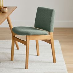 a green chair sitting on top of a white rug next to a wooden dining table