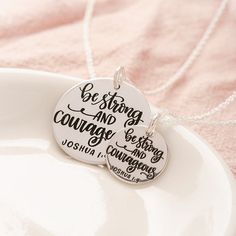 two necklaces with words on them sitting on a plate