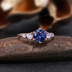 a blue diamond ring sitting on top of a rock