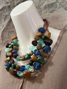 a necklace made with multi colored stones on a mannequin