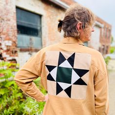 a woman with her back turned to the camera, wearing a brown jacket with black and white squares on it