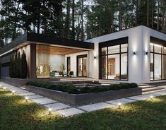 a modern house in the middle of a forest at night with lights on it's windows