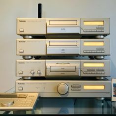 a stack of stereo equipment sitting on top of a glass table next to a remote control