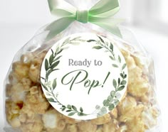 a bag filled with popcorn sitting on top of a white table next to a green bow