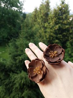 two brown flower rings sitting on top of someone's hand with trees in the background