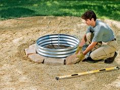 a man kneeling down next to a fire pit