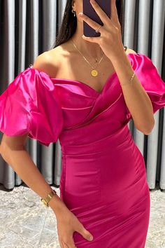 a woman in a pink dress taking a selfie with her cell phone and looking at the camera