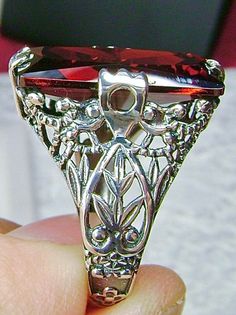 Garnet CZ Sterling Silver RingIntaglio Design#D31 This sterling silver ring is a reproduction of a Victorian filigree antique ring. Inspired by the intricate Victorian designs of the late 1800s and turn of the century, this gorgeous ring is offered in sterling silver. The lovely ring is set with a flawless 7ct Garnet CZ (cubic zirconia) gemstone, by your choice. The baguette shape gemstone is 18mm long by 9mm wide. The ring is 8mm off the finger. The inside of the band is marked 925 for sterling Ornate Ring With Prong Setting, Ornate Prong Set Ring, Ornate Prong Setting Ring, Antique Silver Marquise Jewelry, Vintage Silver Baguette-cut Jewelry, Vintage Silver Baguette Cut Rings, Elegant Oval Crafted Jewelry, Silver Ruby Ring, Art Deco Style For Anniversary, Silver Baguette Cut Ruby Ring For Formal Occasions