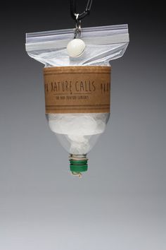 a glass bottle filled with white liquid suspended from a black cord on a gray background