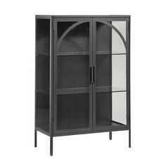 a glass door cabinet with metal legs and an arch design on the front, in grey