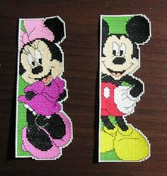 two mickey and minnie mouse bookmarks sitting on top of a wooden table next to each other