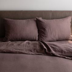 an unmade bed with brown sheets and pillows