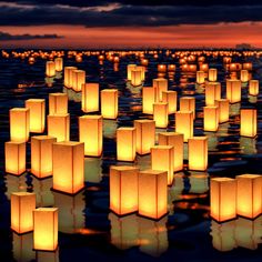 many lanterns floating in the water at night