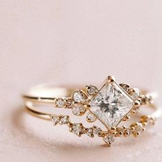 a gold ring with a princess cut diamond surrounded by small white and clear diamonds on it