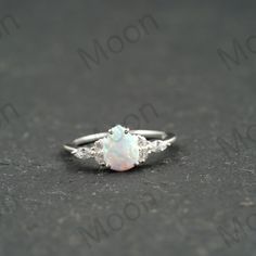 a white opal and diamond ring sitting on the ground