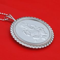 "A gorgeous sterling silver necklace, set with an authentic 1 oz Silver Round - Ganesha. Obverse: Traditional image of Ganesha attended by a mouse, which is commonly seen. Reverse: Hindi text for \"Hinduism,\" along with the weight, purity and year of issue. The coin bezel frame is well designed with classic ropes, about 2.32\"(59mm) x 1.84\"(47mm), and made of solid 925 sterling silver. It comes with a 24\" 925 sterling silver chain and also a beautiful gift box, so the pendant is ready to wear Engraved Temple Jewelry As A Gift, Traditional Medallion Jewelry With Polished Finish, Traditional Medallion Necklace With Polished Finish, Traditional Polished Medallion Jewelry, Silver Engraved Jewelry For Diwali, Round Pendant Jewelry Gift For Diwali, Round Pendant Jewelry For Diwali Gift, Diwali Gift Round Pendant Jewelry, Diwali Gift Round Pendant Necklace