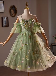 Mellow yet striking, this soft green homecoming dress is a true testament to the art of detailed craftsmanship and design. The gown is adorned with an exquisite array of hand-embroidered flowers, each stitch contributing to a tapestry of floral elegance that seems to whisper tales of springtime serenades. The off-shoulder sleeves crafted from the same sheer material as the overlay add a modern twist to the classic silhouette, providing a flattering look for all who wear it. Beneath the floral embroidery, the dress extends into a full, flowing skirt that promises to sway elegantly at every turn. Perfect for those who appreciate a blend of contemporary fashion and timeless details, this dress ensures you'll look and feel spectacular at your next formal gathering. Green Short Prom Dress, Homecoming Dresses Green, Green Silhouette, Dance Dress Ideas, Floral Homecoming Dresses, Prom Dresses 2016, Green Homecoming Dresses, Green Tulle, Cute Homecoming Dresses