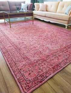 a living room area with couches and rugs on the wooden floor, including a sofa