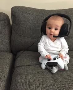 a baby is sitting on a couch with a video game controller in it's mouth