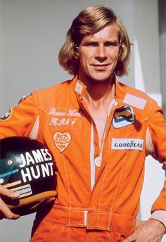 a man in an orange racing suit holding a helmet