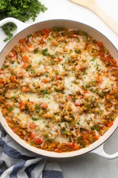 a casserole dish filled with meat, vegetables and cheese on a white surface