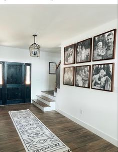 a room with pictures hanging on the wall and stairs leading up to it's entrance