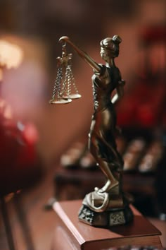 a statue of lady justice holding the scales of justice on top of a wooden table