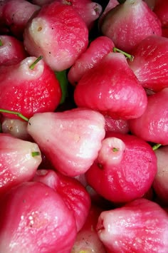 some red fruit with green leaves on it and water droplets all over the top of them