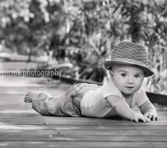 a little boy laying on the ground wearing a hat