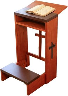 a small wooden desk with a cross on it and a book sitting on the top