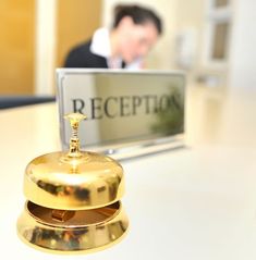 a gold bell sitting on top of a white table in front of a reception sign