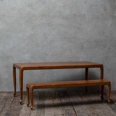 a wooden bench sitting on top of a hard wood floor next to a cement wall