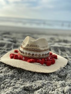 Decorated straw hat, fits size medium to small. Our Dahlia hat is a beautiful and comfortable must have for any occasion. It's decorated with red pom pom, gold and silver seashells, brown button trim and camel suede trim. Each hat is 100% made by hand and made by daily inspirations. No two hats are the same. Casual Holiday Hat With Curved Brim, Casual Curved Brim Hats For Holiday, Casual Curved Brim Holiday Hat, Casual Curved Brim Hat For Holidays, White Bohemian Wide Brim Boater Hat, Toquilla Straw Fedora With Curved Brim For Festivals, White Bohemian Sun Hat One Size, White Bohemian Sun Hat, Red Brimmed Mini Hat For Beach