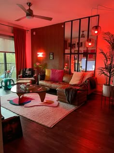 a living room filled with furniture and red lighting on the walls, along with large windows