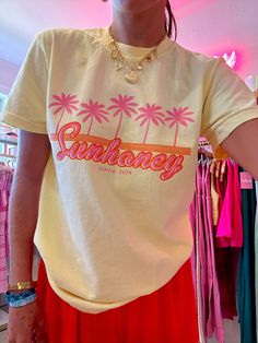 Our EXCLUSIVE Sunhoney Retro Palm Tee in Yellow screams summer vibes with its playful graphic of pink palm trees and orange retro design. Featuring our classic logo in a stunning orange and pink colorway, this tee is the perfect addition to your warm weather wardrobe. This summer graphic is printed on Comfort Colors tee and is a full length, shirt is tucked in for photos for styling purposes. Get yours now and be prepared to wear all summer long! Product is made to order: available for pick up/s Cheap Peach T-shirt With Graphic Print, Affordable Multicolor Retro Print T-shirt, Tropical T Shirt Designs, Print On Demand Clothing, Tshirt Product Photo, Yellow T-shirt For Spring Vacation, Retro Printed Summer T-shirt, Retro Summer T-shirt With Front Print, Vintage Printed T-shirt For Summer