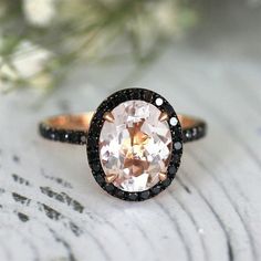 a ring with an oval shaped morganite surrounded by black and white diamonds