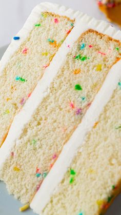 a slice of cake with white frosting and sprinkles