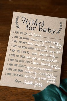 a handwritten wish for baby card on a wooden table with a green plant next to it